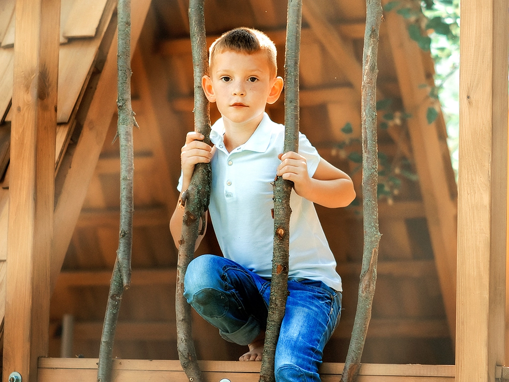 little boy playing in a treehouse at a forest park